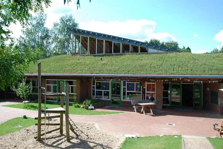 Modernes Gebäude mit einem begrünten Dach und Spielplatz.