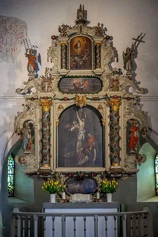 Prunkvoller, historischer Altaraufsatz mit religiösen Gemälden und Schnitzereien im Kircheninneren.