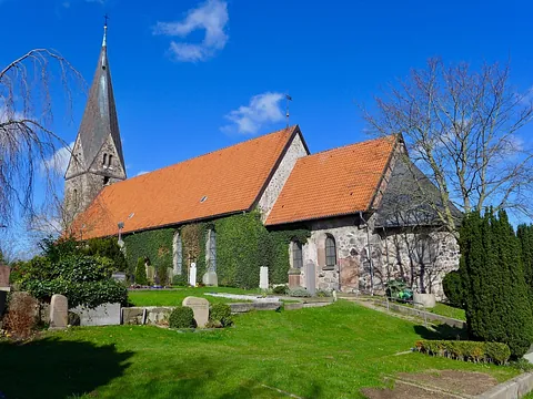 Außenansicht der Borby Kirche mit Steinmauern, rotem Dach und Friedhof.