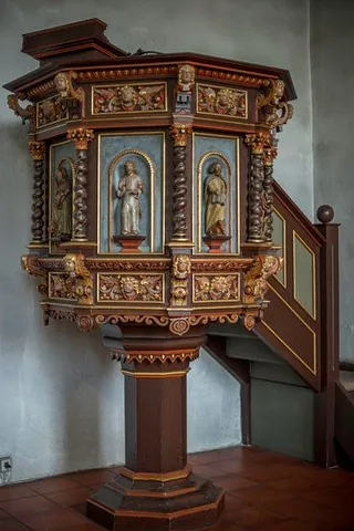 Aufwendige, geschnitzte Holzkanzel mit Figuren im Inneren einer Kirche.