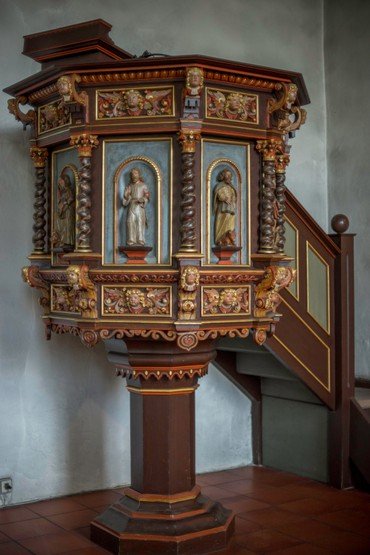 Aufwendige, geschnitzte Holzkanzel mit Figuren im Inneren einer Kirche.